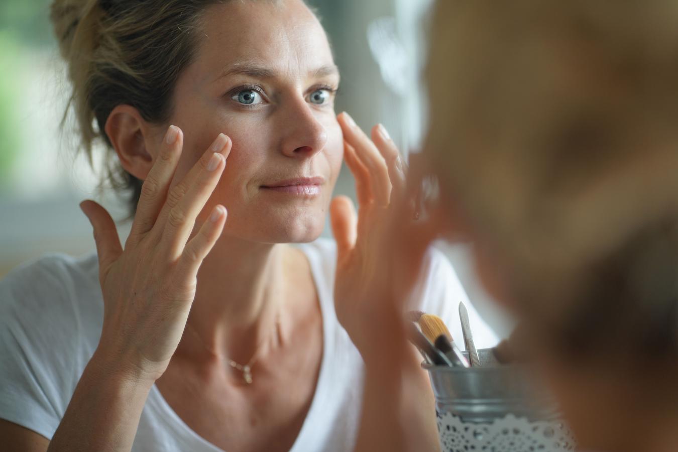 woman looking at her face in the mirror chemical peel pores says dr clay mask laser treatments