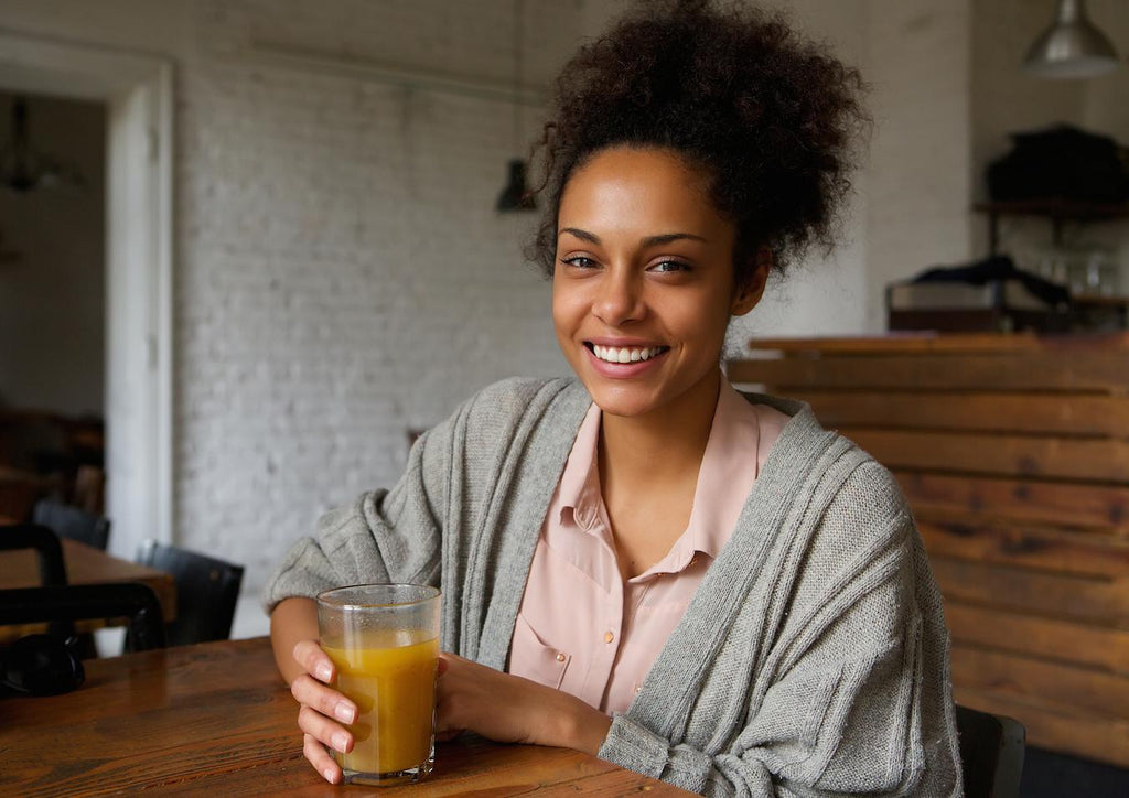 woman smiling drinking an orange drink ginger turmeric tea turmeric benefits turmeric ginger extract turmeric ginger turmeric ginger root decrease nausea potential health benefits