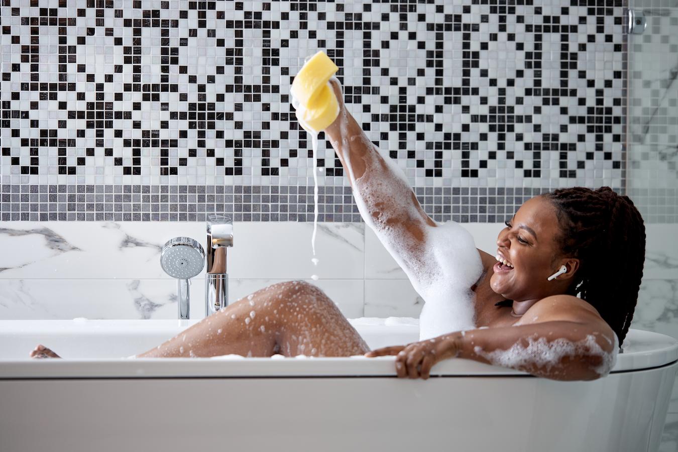 woman taking a bath smiling best body cleanser body lotion cleaning agent different benefits unique formulations warmer climates surface tension antibacterial properties body washes