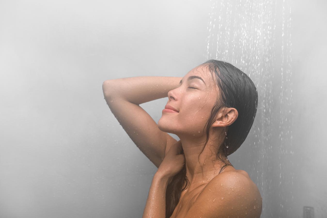 woman taking a steamy shower at home sebum production hyaluronic acid helps calm breakouts sun damage dark spots