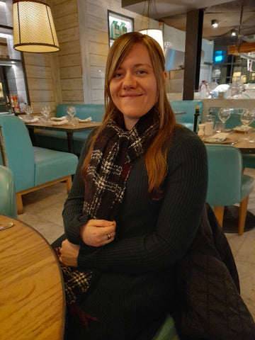 Kaylie, the founder of Spellweaver Digital Solutions, seated at Gino D'Acampo's restaurant in Manchester, November 2021, smiling and enjoying the vibrant atmosphere.