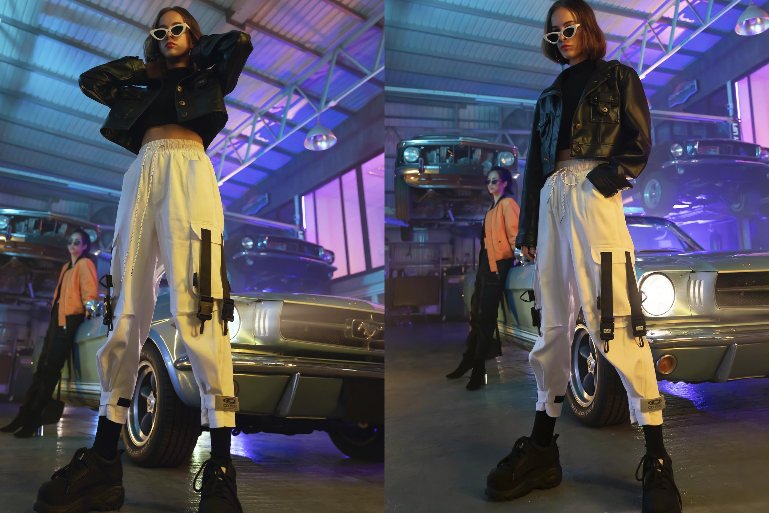 A female model in black jacket and white cargo pants is standing next to a car.