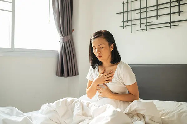 Femme sur son lit qui a la nausée