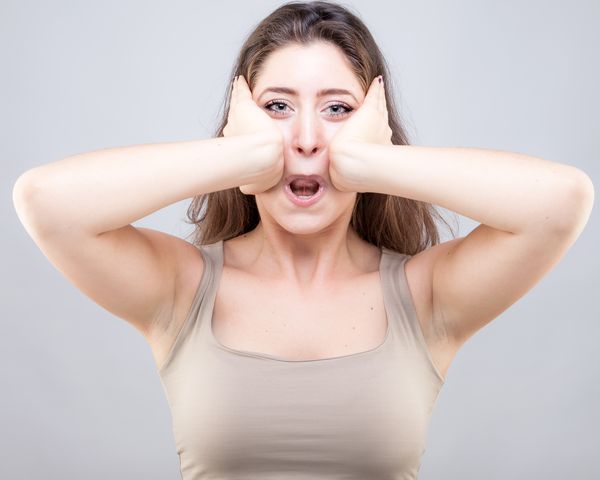 Woman presses her cheekbones with the palms of her hands