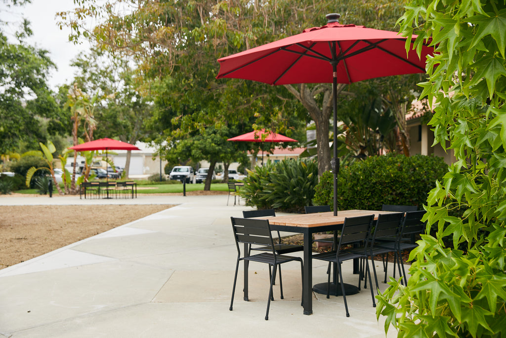 Wooden outdoor dining table with chairs and red umbrella