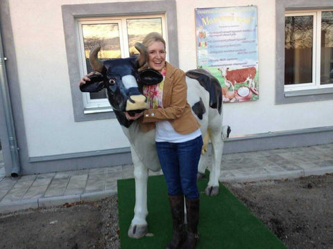 Cindy smiling as she poses next to a statue of a cow in support of Heifer International