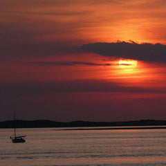 Cape Cod at sunset with a boat on the water.