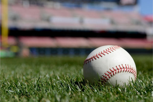 A ball in the grass in front of a baseball stadium