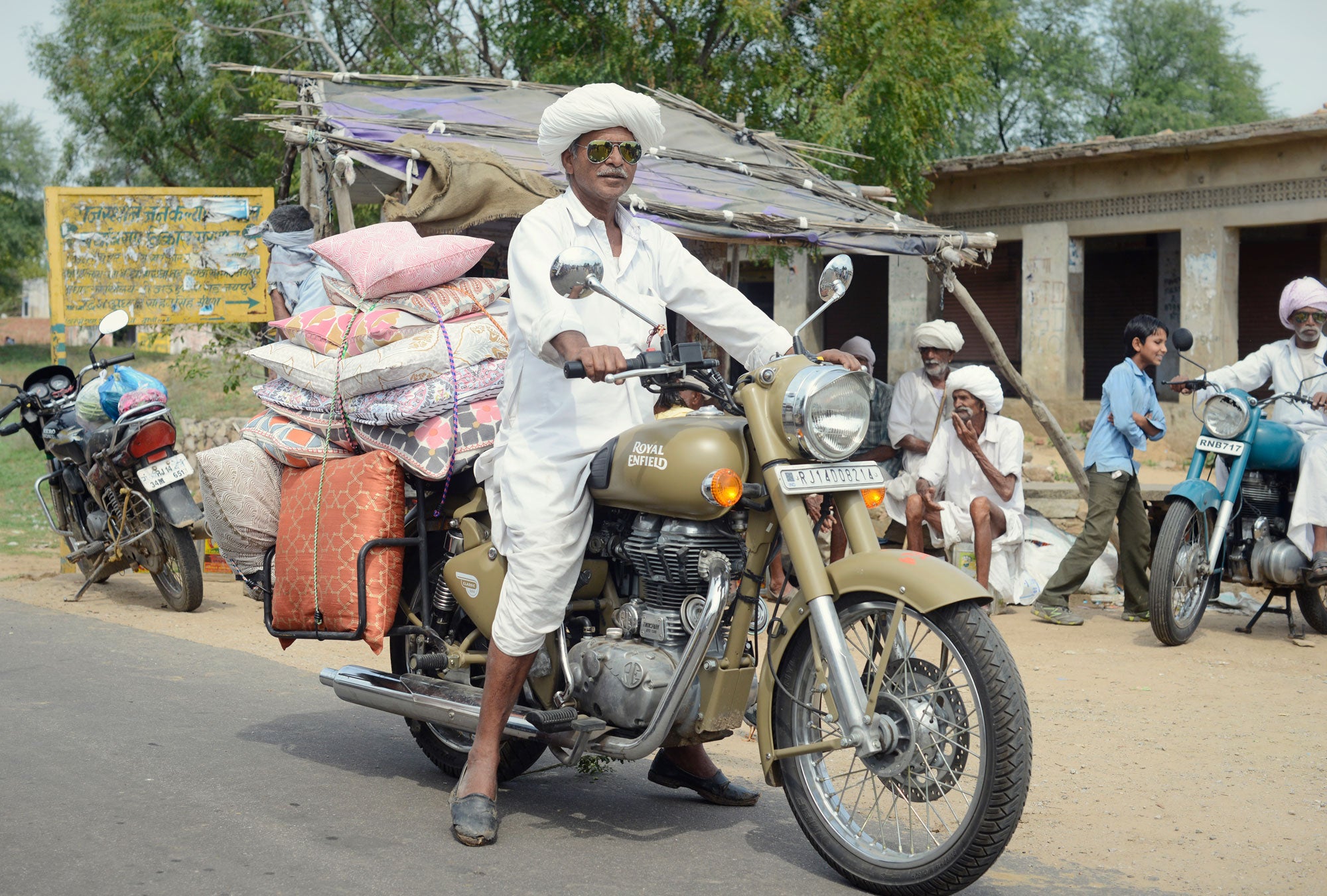 A motorcycle rider carries a stack of pillows as cargo.