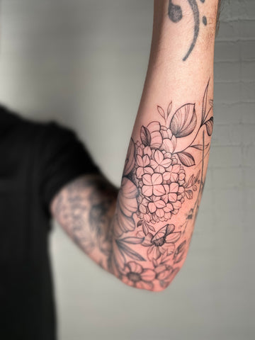 floral arm tattoo by Lu Loram Martin, in Toronto, Canada.