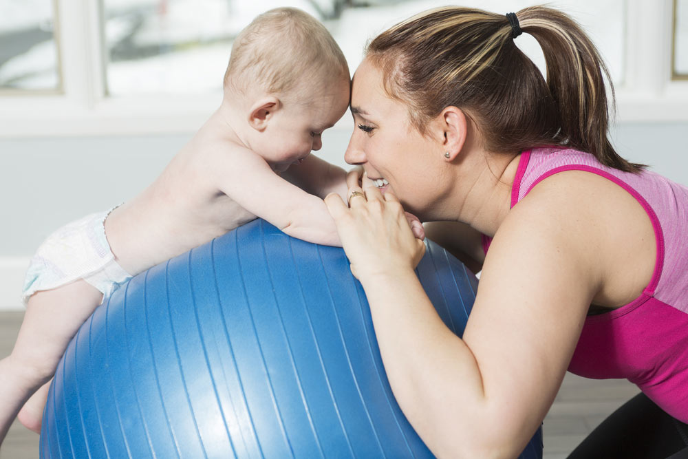 mum using yoga ball with newborn baby postpartum