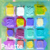 Farbpalette mit 16 Vertiefungen mit überwiegend grünen, violetten und gelben Farbvermischungen