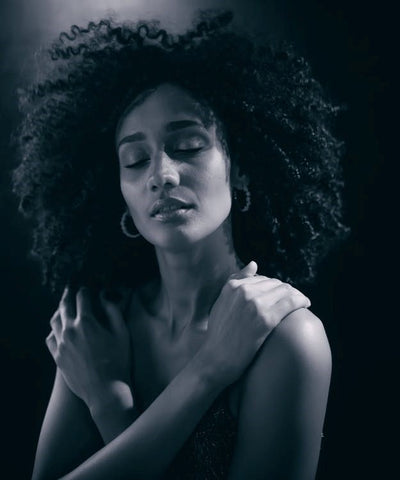 A woman with curly hair posing with her eyes closed