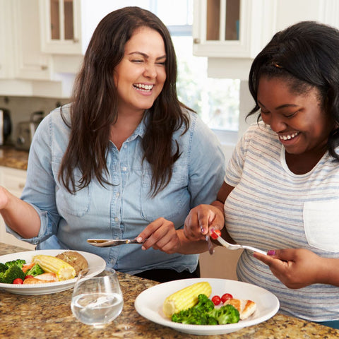 two woman smiling sharing a meal