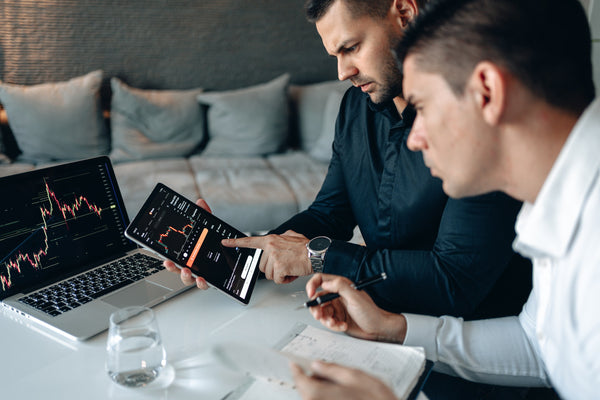 Two men with a tablet sitting in front of a laptop 