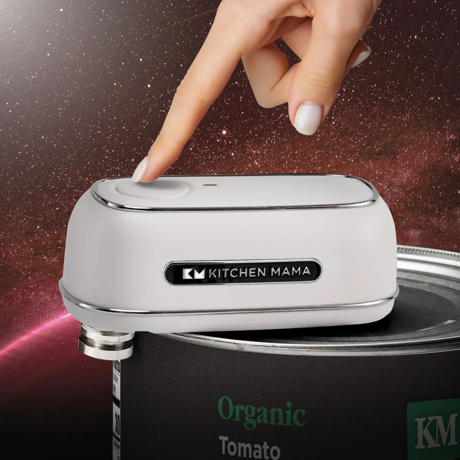 Close-up of white Kitchen Mama Orbit One on a black Organic Tomato can, hand near button, galaxy-style background.