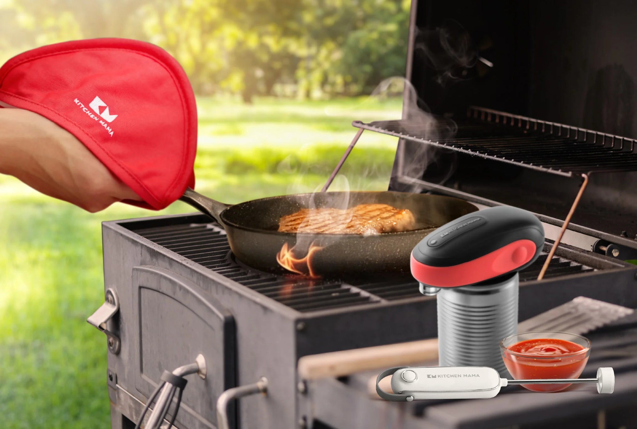 A person using a red Kitchen Mama pot holder to hold a pan on a grill, with the One-to-Go can opener and SilkWhisk milk frother shown nearby beside a bowl of BBQ sauce.