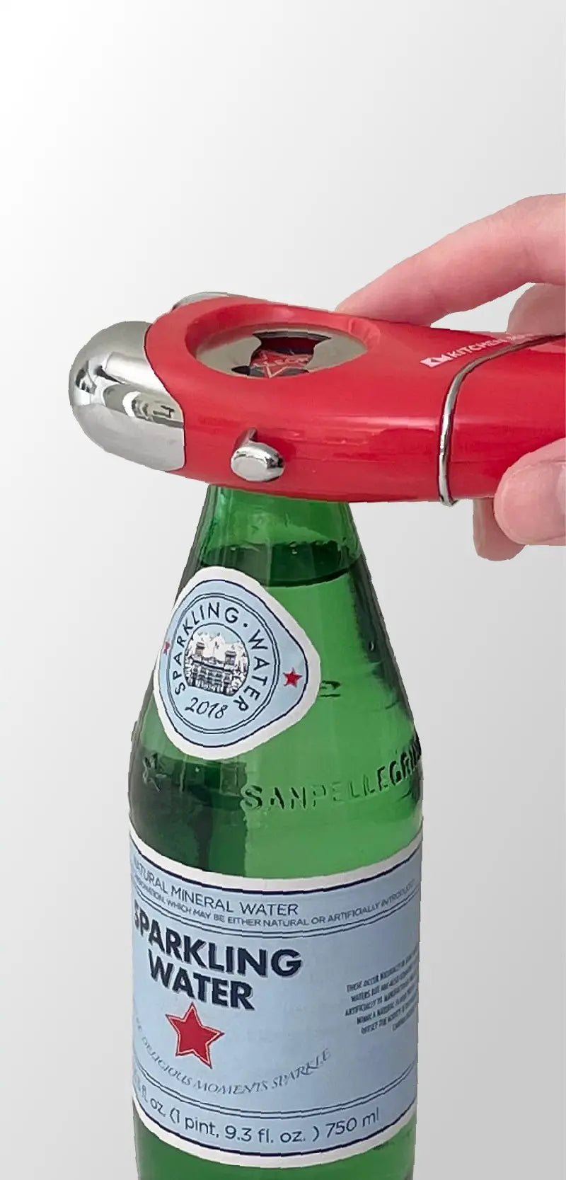 A hand using a red bottle opener on a sparkling water bottle, showcasing the opener's sleek design and the bottle's labels.