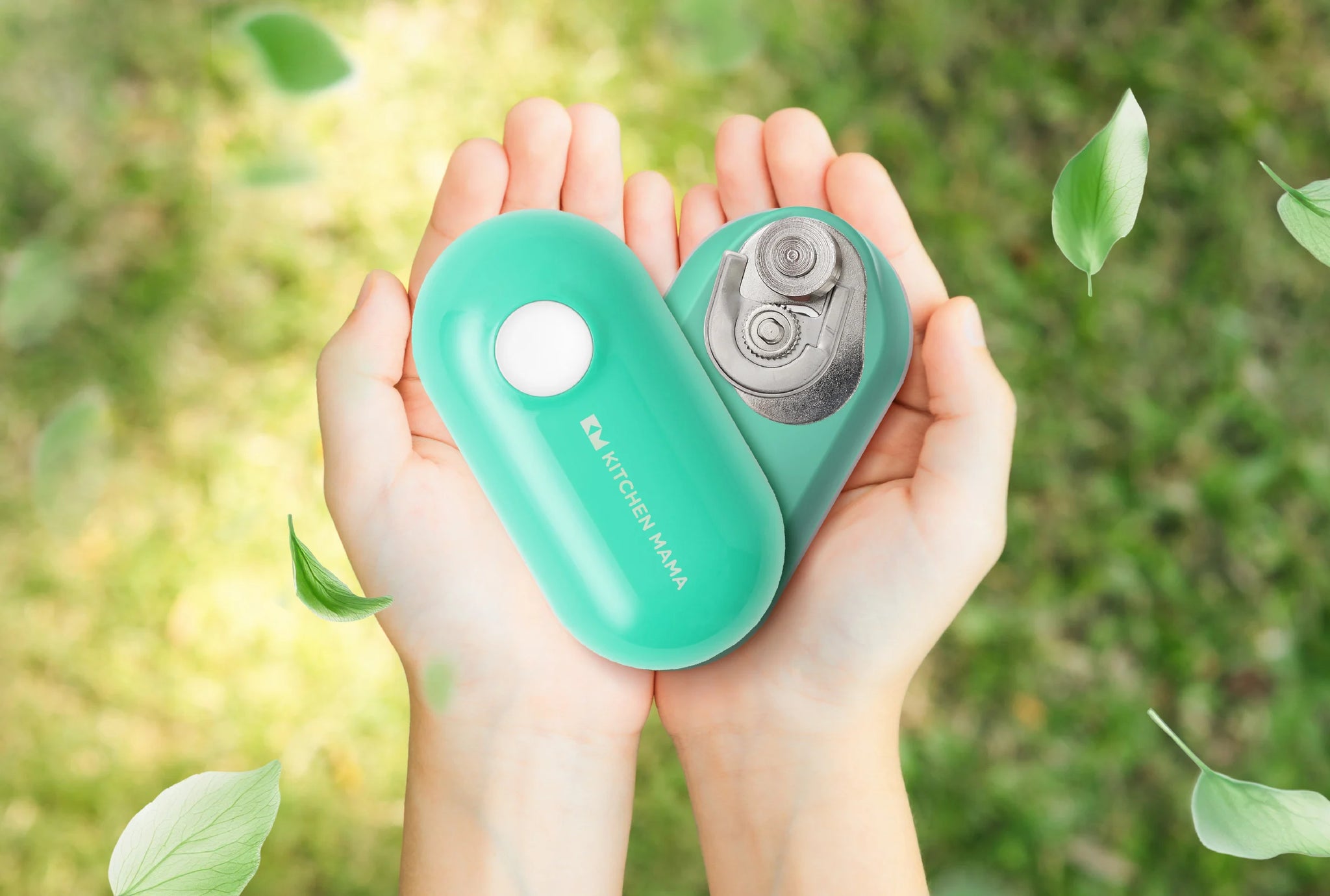 Hands gently holding a green Kitchen Mama can opener outdoors, surrounded by floating leaves.