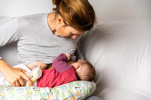 Mother breastfeeding her child while using a breastfeeding pillow to relieve back pain.
