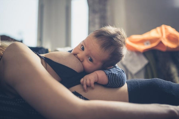 Mother breastfeeding her child while lying down on the sofa