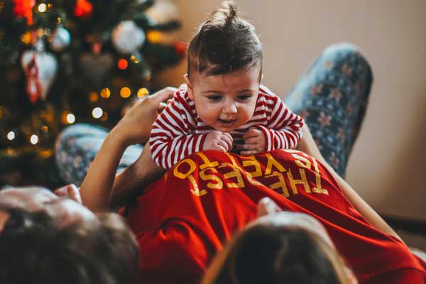 Baby lies on top of mother in Christmas outfit