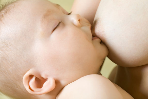 Baby having eyes closed and getting breastfed