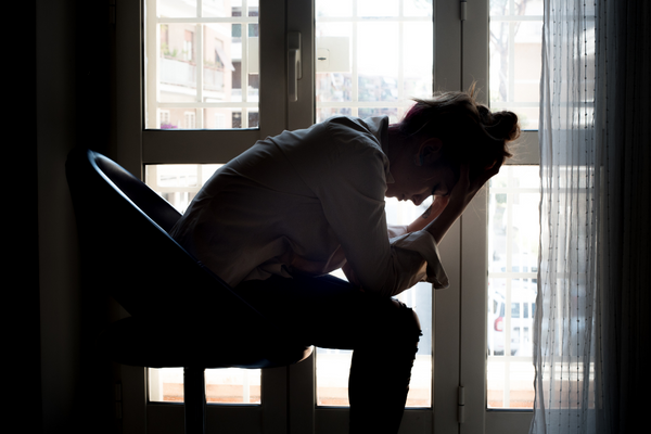 A woman feeling postpartum depression and rests her head on her hands