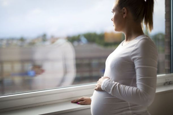 a pregnant woman looking out of a window