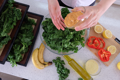 a person pouring dressing into a bowl of vegetables