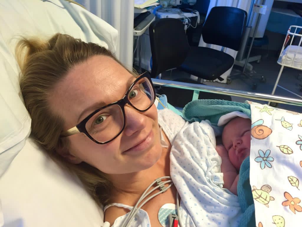 Co-founder Laura at a hospital after giving birth holding her newborn baby