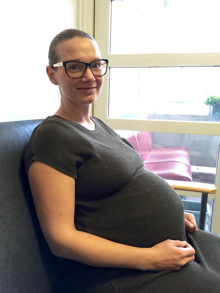 Laura pregnant sitting on a sofa