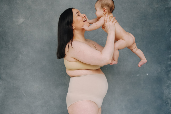 Mother holding child in the air, emphasizing the importance of postpartum body positivity