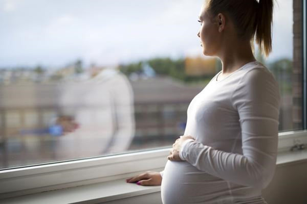a pregnant woman having pelvic pain and looking out of a window