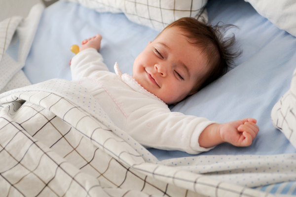 A peacefully sleeping baby with a joyful smile on their face