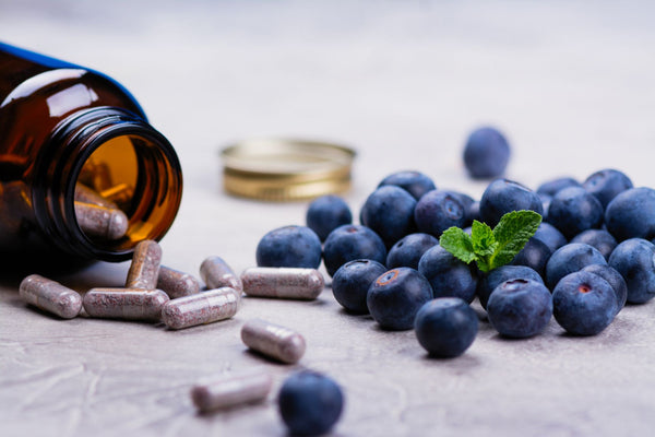 Fresh blueberries and a bottle of multivitamins, highlighting their benefits for the health of both mother and baby