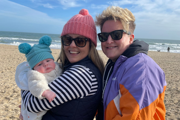 Leah and Kelly smiling with their newborn