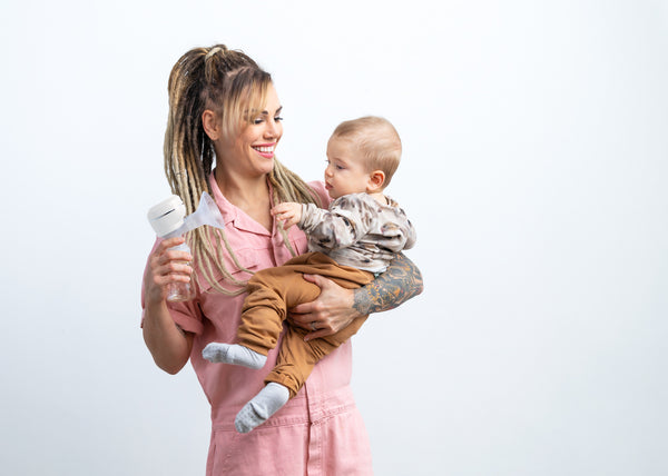 Eva Wahlström is holding Lola&Lykke Electric Breast Pump by her right hand and smiling at her baby
