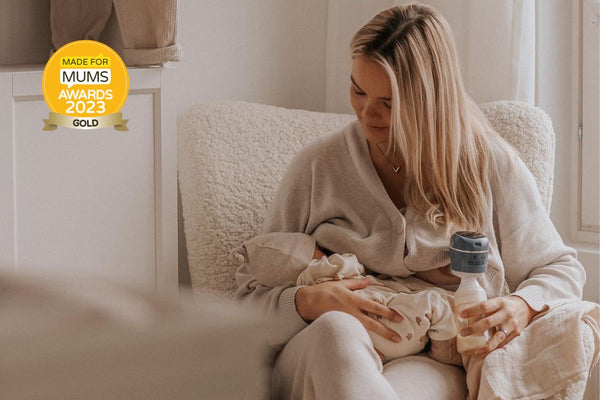 A woman sitting on a chair and using the Lola&Lykke Smart Electric Breast Pump to express milk