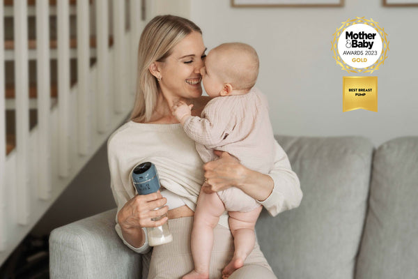A mum holding a baby and using Lola&Lykke electric breast pump