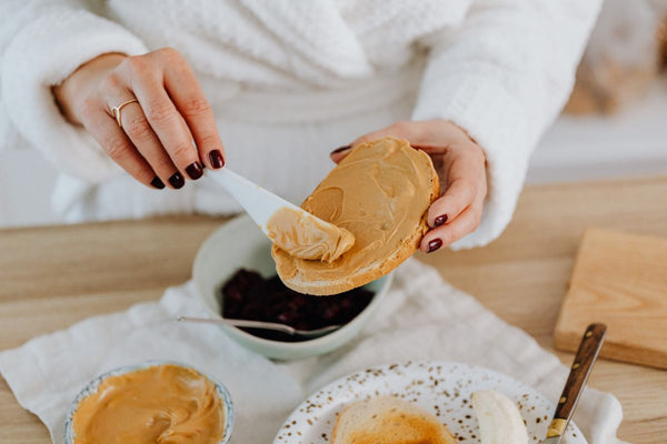 woman spreads peanut butter on her bread