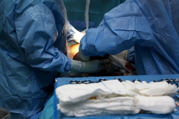 A c-section delivery taking place in a hospital, with two doctors carefully performing the procedure