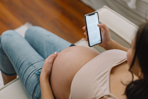 Pregnant woman using a remote doctor system on her phone.