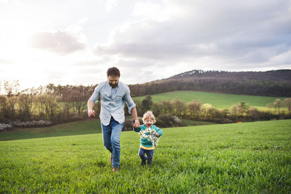 dad and son walking hand in hand in the meadow