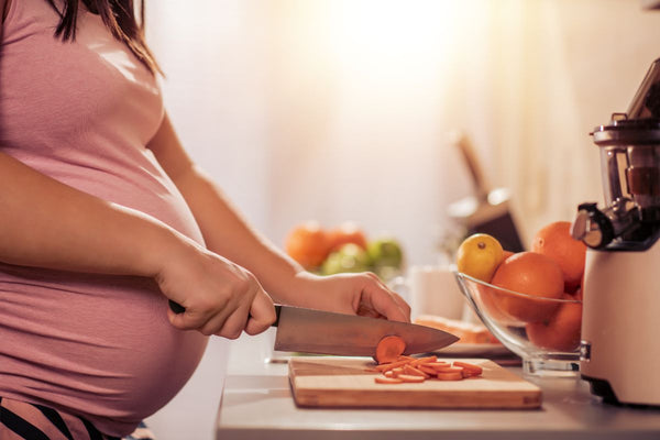 A pregnant woman delicately cuts fresh carrots