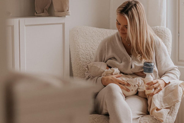 Mother pumping with the Lola&Lykke Smart Electric Breast Pump while holding her baby