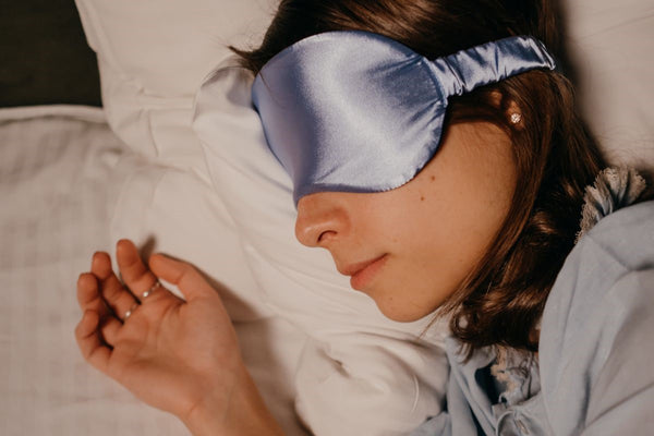 A woman peacefully sleeping with an eye mask, a recommended item to include in the hospital bag for labor