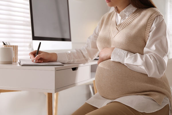 a pregnant woman is sitting and writing her diary