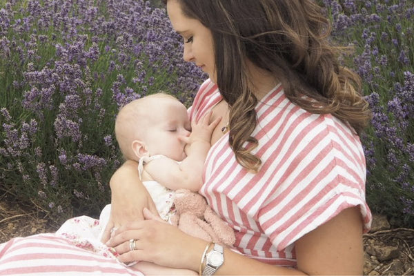 Madison breastfeeding her baby in a field full of flowers, enjoying the beauty of nature while nurturing her little one