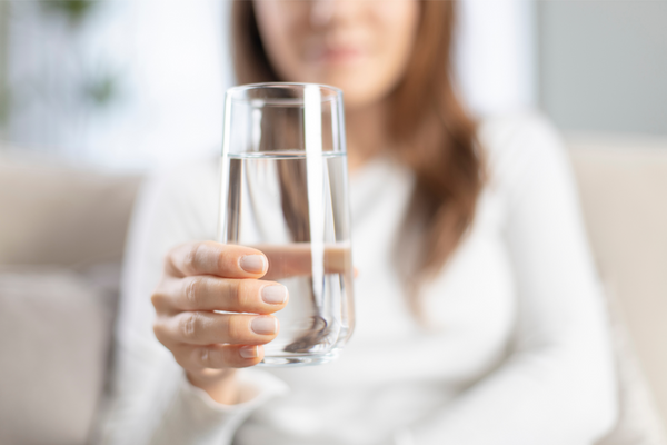 A mother gently cradles a glass of refreshing water, prioritizing hydration as part of her post-C-section recovery journey